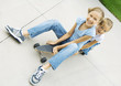 Two girls sitting on skateboard together