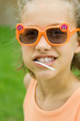 Girl wearing sunglasses, lollipop in mouth, portrait