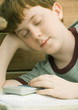 Boy dozing off as he does homework