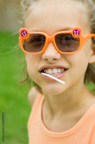 Photo: Girl wearing sunglasses, lollipop in mouth, portrait Girl wearing sunglasses, lollipop in mouth, portrait