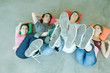 Four teen friends lying on backs on floor, holding up legs, focus on soles of shoes