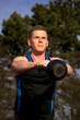 Young man doing kettlebell exercise outside in park