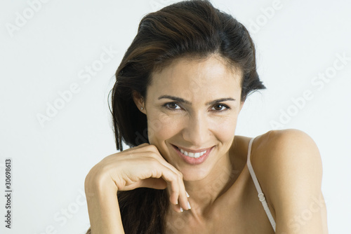 Photo: Woman smiling at camera, hand by chin, portrait Woman smiling at camera, hand by chin, portrait