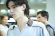 Male college student in library, looking away, head and shoulders