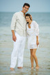 Photo: Man and young female companion on beach, standing together, looking at camera, full length Man and young female companion on beach, standing together, looking at camera, full length
