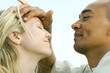 Man placing hand on woman's forehead, both with eyes closed, side view