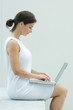 Photo: Woman sitting, using laptop computer, side view Woman sitting, using laptop computer, side view