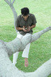 Man sitting in tree, holding bird's nest with eggs in hands, looking down