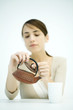 Young woman looking at teapot, lifting lid, focus on foreground