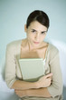 Woman holding book, looking at camera, portrait