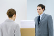 Photo: Young professionals standing face to face, documents stacked on cardboard box between them Young professionals standing face to face, documents stacked on cardboard box between them