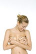 Photo: Woman holding silicone implants over breasts, looking down, smiling Woman holding silicone implants over breasts, looking down, smiling
