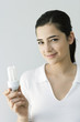 Young woman holding energy efficient light bulb, smiling at camera