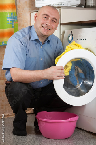 Photo: man loading the washing machine man loading the washing machine