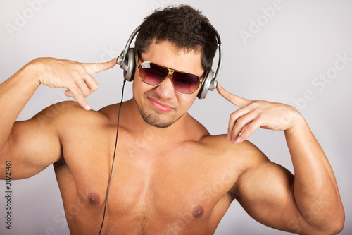 Photo: handsome man listening to music on headphone against natural bac handsome man listening to music on headphone against natural bac