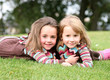 Sisters lying on grass holding each other close