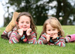 Sisters lying on grass smiling at camera