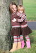 Two sisters hugging beside a tree