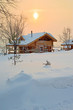 the photo shows a wooden house in the snow