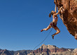 Female rock climber clinging to a cliff.