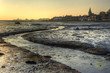 Low tide harbour at sunset with nearby town in distance nad stre