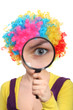 Girl in colored curly wig looking through a magnifying glass