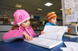 Little boy in striped cap and girl in outerwear reading a book