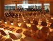 several rows of white plastic chairs; people in light conference