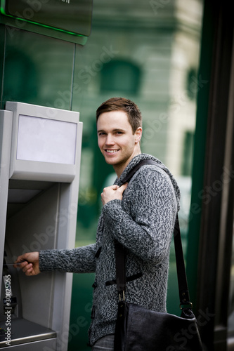 Photo: A young man using a cash machine A young man using a cash machine