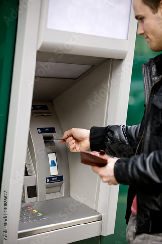 Foto: A young man using a cash machine A young man using a cash machine