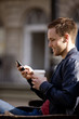 A young man sitting on a bench, using his mobile phone