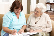 Senior Woman In Discussion With Health Visitor At Home