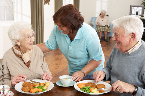 Foto: Senior Couple Being Served Meal By Carer Senior Couple Being Served Meal By Carer