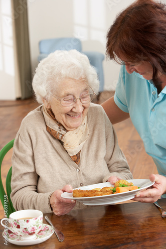 Photo: Senior Woman Being Served Meal By Carer Senior Woman Being Served Meal By Carer