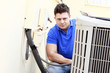 Technician inspects an AC unit