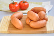 Delicious sausages on a cutting board and ripe tomatoes Delicious sausages on a cutting board and ripe tomatoes
