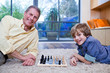 Grandfather playing chess with grandson on rug