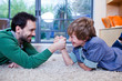 Father and son arm wrestling on rug