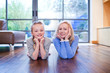 Grandmother and granddaughter laying on wooden floor with head in hands