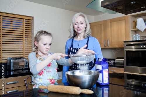 Photo: Grandmother and granddaughter baking in kitchen Grandmother and granddaughter baking in kitchen