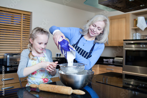 Photo: Grandmother and granddaughter baking in kitchen Grandmother and granddaughter baking in kitchen