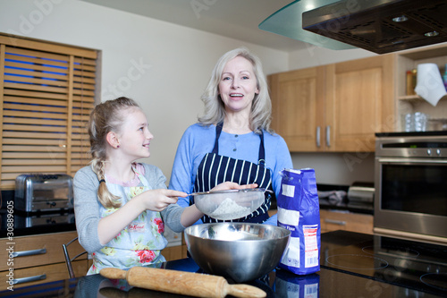 Photo: Grandmother and granddaughter baking in kitchen Grandmother and granddaughter baking in kitchen
