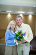 Smiling couple holding bunch of flowers
