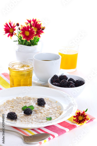 Photo: Oatmeal with honey and blackberries isolated on white background Oatmeal with honey and blackberries isolated on white background