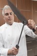Mid- adult chef sharpens knife