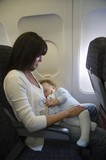 Photo: Mother and toddler on an aeroplane with the window blind down. The toddler is asleep cuddling a toy rabbit, while the mother looks at them Mother and toddler on an aeroplane with the window blind down. The toddler is asleep cuddling a toy rabbit, while the mother looks at them