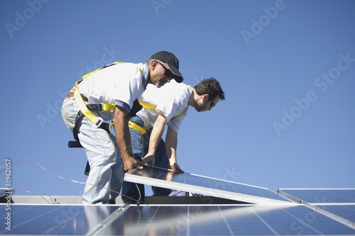 Photo: Two men lifting a solar panel Two men lifting a solar panel