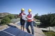 Photo: Two business people on a rooftop next to solar panelling, holding up a set of plans Two business people on a rooftop next to solar panelling, holding up a set of plans