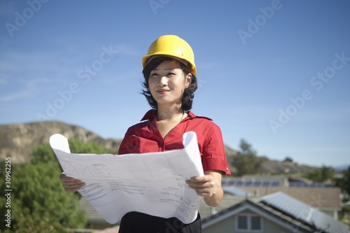 Photo: A business lady on a rooftop with plans in her hand A business lady on a rooftop with plans in her hand