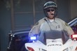 Patrol officer sits on motorcycle with hazrd lights lit